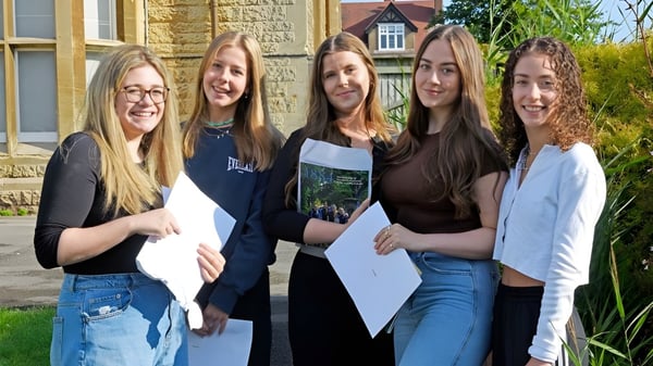 Fünf Schülerinnen der Kingsley School stehen gemeinsam vor einem alten Steinbau mit Gras im Hintergrund.