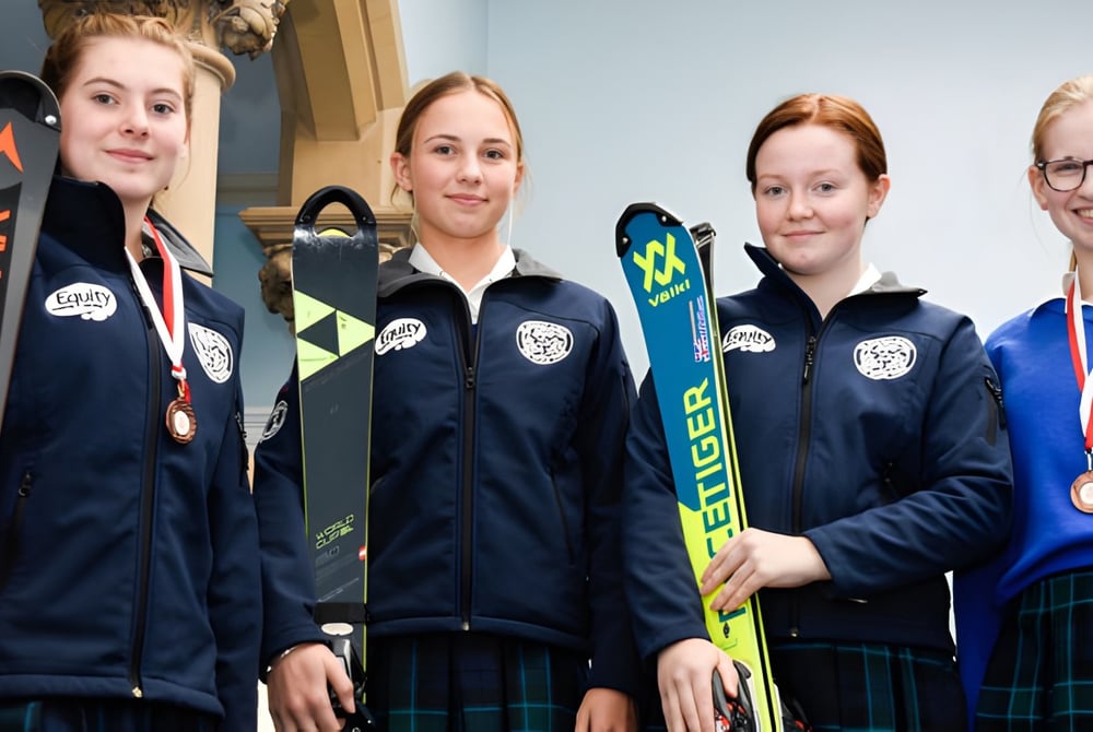 Vier Schülerinnen der Kingsley School stehen mit Skiausrüstung in einem Trainingszentrum.