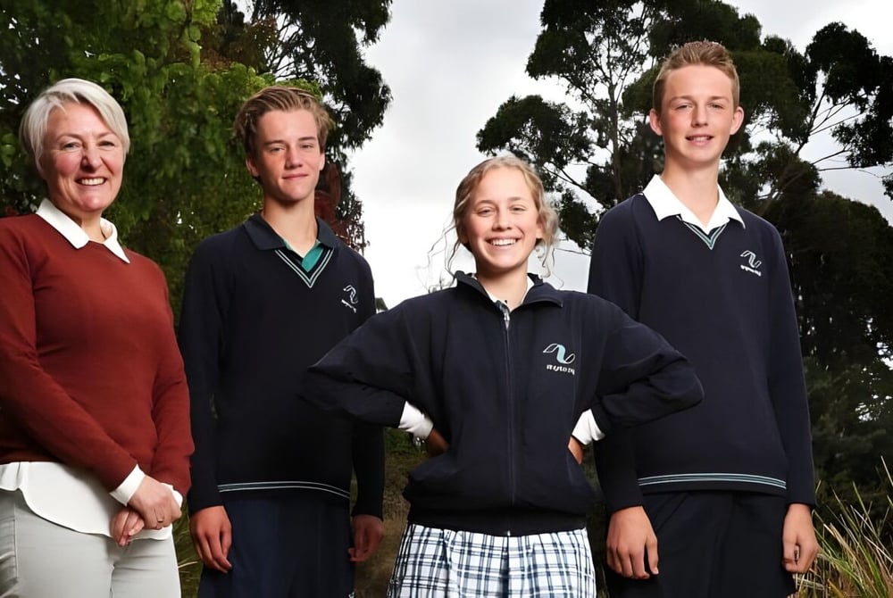 Vier Personen stehen draußen vor Bäumen auf dem Gelände der Kingston High School.