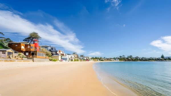 Bunte Strandhäuser an der Küste in der Nähe von Kingston High School bei klarem Himmel.