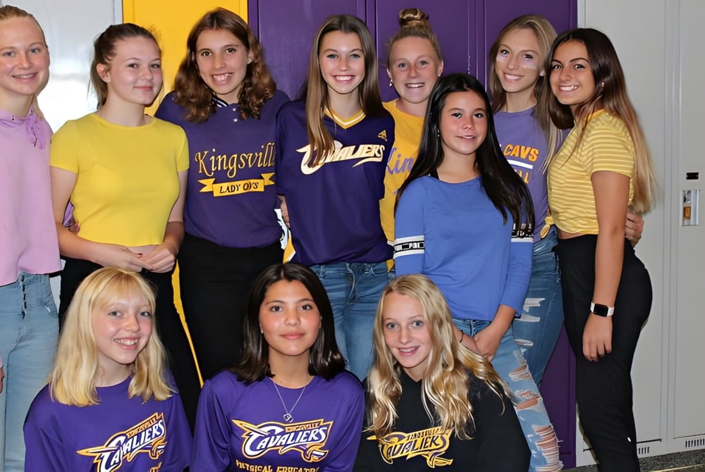 Eine Gruppe Schülerinnen posiert vor einem bunten Hintergrund auf dem Campus der Kingsville District High School.