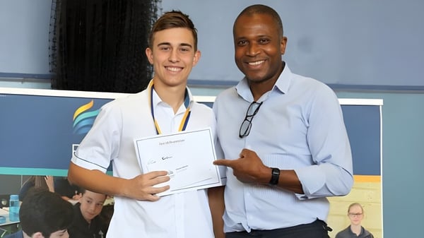 Ein Schüler des Kinross College hält ein Zertifikat und steht neben einem älteren Mann.