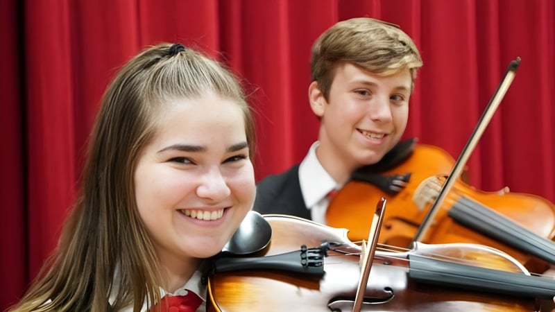 Schüler der Kirwan State High School spielen gemeinsam Violine auf einer Bühne vor rotem Vorhang.