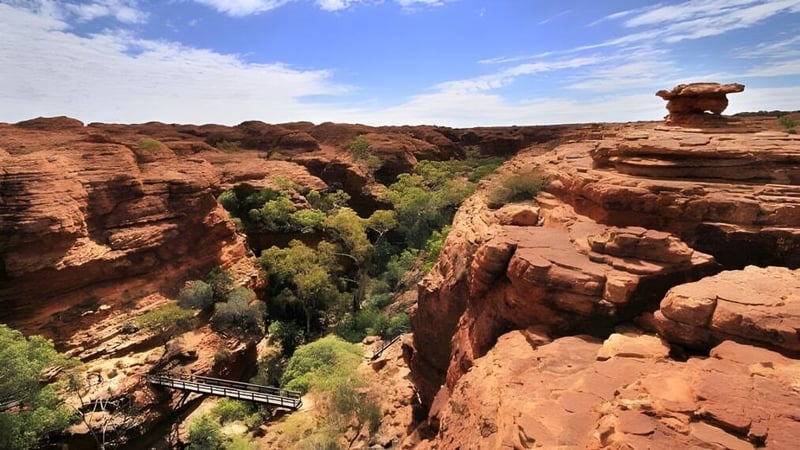 Landschaft mit Canyon und Fußgängerbrücke auf dem Gelände der Kirwan State High School unter einem bewölkten Himmel.