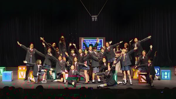 Eine Gruppe von Schülerinnen und Schülern der Korea International School steht auf der Bühne und führt eine Theateraufführung auf.