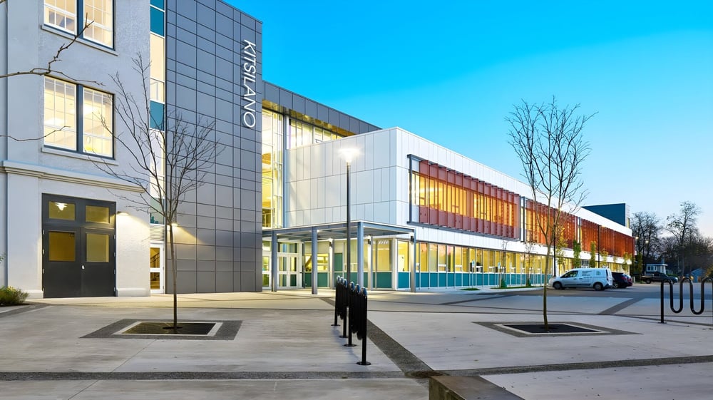 Das moderne Hauptgebäude der Kitsilano Secondary School mit Glasfassade und bunten Akzenten unter blauem Himmel.