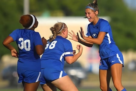 Eine Gruppe junger Fußballspielerinnen feiert gemeinsam auf dem Spielfeld der Kokomo High School.