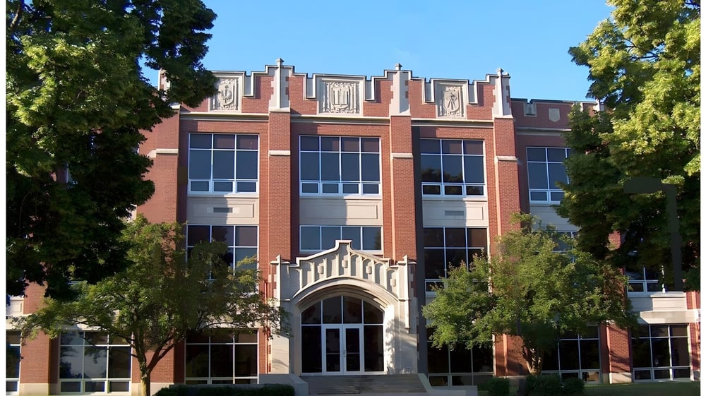 Das große Backsteingebäude mit Bogenfenstern der Kokomo High School steht umgeben von Bäumen und Grünflächen.