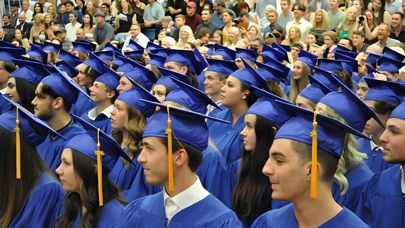 Eine große Gruppe von Absolventinnen und Absolventen in blauen Talaren sitzt bei der Abschlussfeier der Kootenay River Secondary.