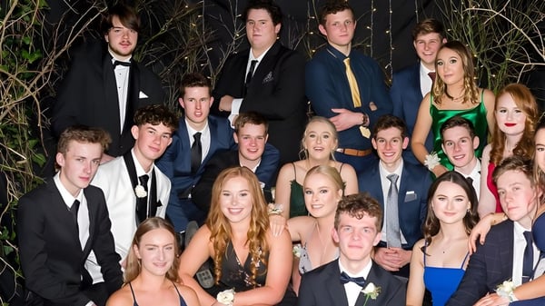 Eine Gruppe von Schülerinnen und Schülern des Kuranui College in formeller Kleidung posiert draußen vor Bäumen.