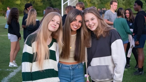 Eine Gruppe von Schülerinnen mit langem Haar steht lachend auf einer Wiese auf dem Gelände der La Lumiere School.