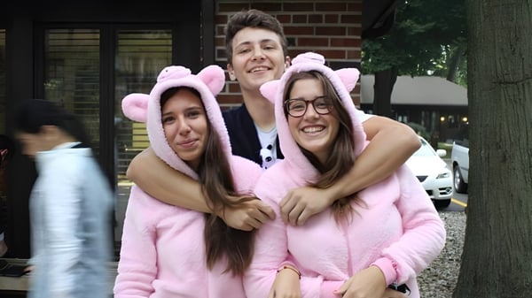 Drei Schülerinnen der La Lumiere School umarmen sich vor einem Ziegelgebäude und lächeln.