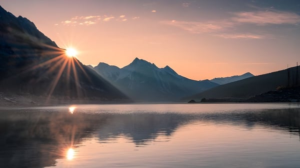 Ein ruhiger Bergsee spiegelt die Berge und den Sonnenuntergang außerhalb des Campus der La Salle Secondary School wider.