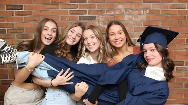 Eine Gruppe junger Frauen in Abschlusskleidung posiert vor einer Backsteinwand auf dem Gelände der École secondaire publique L'Académie de la Seigneurie.
