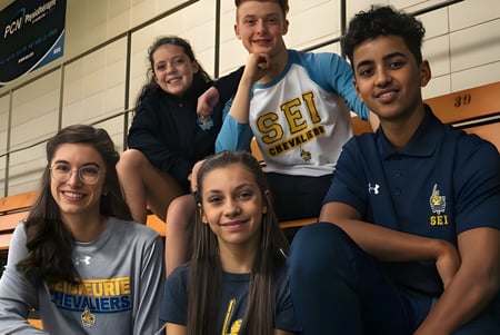 Eine Gruppe von Schülerinnen und Schülern der École secondaire publique L'Académie de la Seigneurie posiert in der Sporthalle.