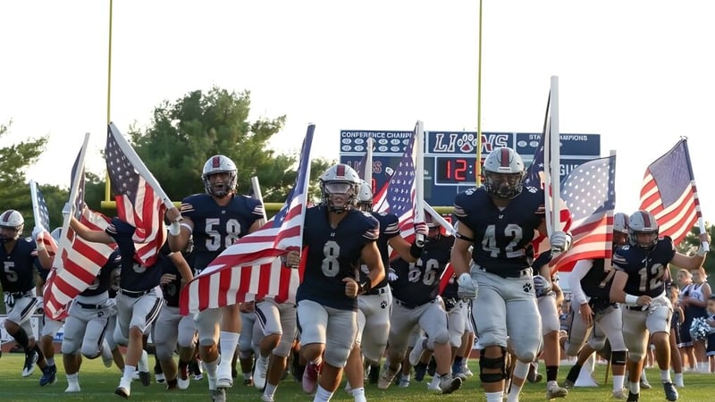 Eine Gruppe Football-Spieler läuft mit amerikanischen Flaggen auf das Spielfeld der Lacey Township High School.