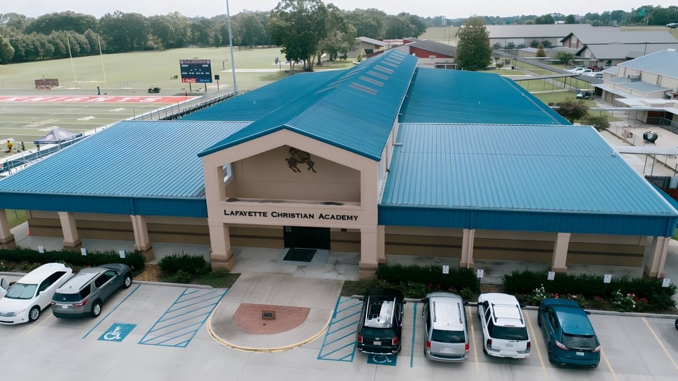 Das Hauptgebäude der Lafayette Christian Academy mit blauem Metalldach und Parkplatz im ländlichen Umfeld.