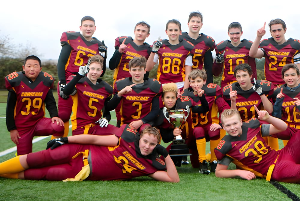 Eine Gruppe von Schülerinnen und Schülern der Lake Cowichan Secondary School posiert in Sportkleidung auf einem Rasenfeld.