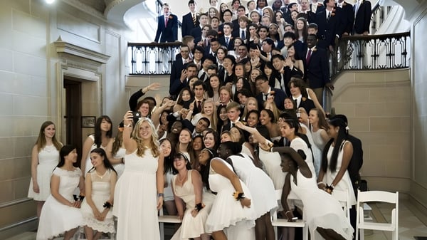 Eine große Gruppe von Personen in formeller Kleidung versammelt sich in der repräsentativen Aula der Lake Forest Academy.