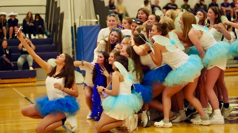 Schülerinnen der Lake George Junior-Senior High School in bunten Tanzkostümen posieren gemeinsam auf der Bühne.