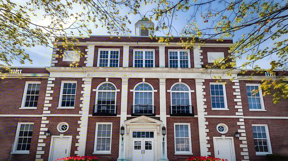 Das historische Ziegelgebäude der Lake George Junior-Senior High School umgeben von grünen Bäumen unter blauem Himmel.