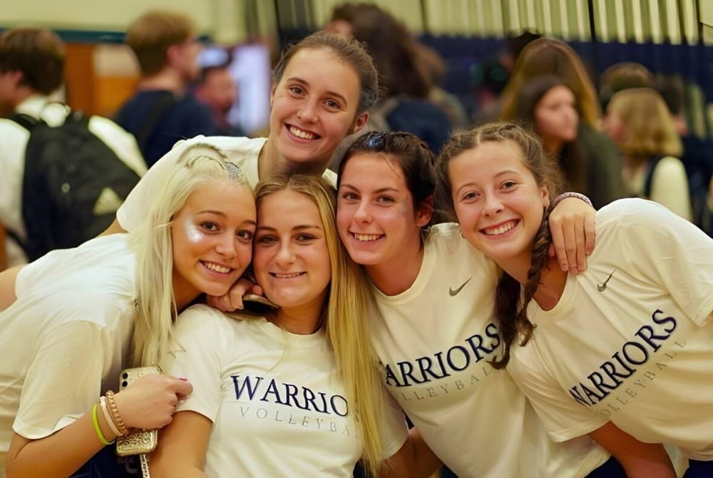 Eine Gruppe lächelnder Schülerinnen in Warriors-T-Shirts posiert gemeinsam an der Lake George Junior-Senior High School.