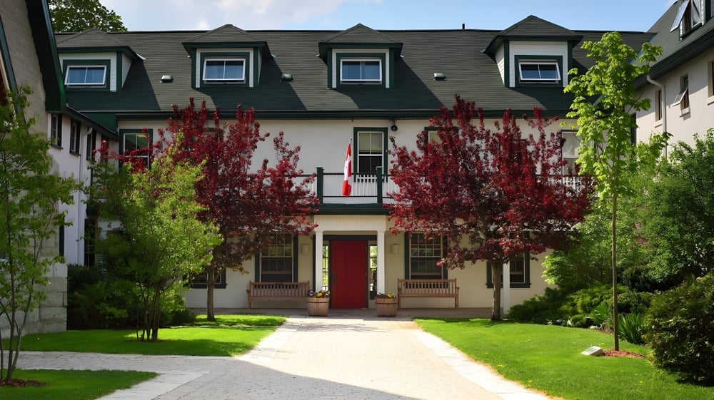 Das mehrstöckige Gebäude mit grünem Dach von Lakefield College School ist von grünen und roten Bäumen umgeben.