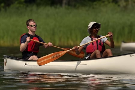 Zwei Personen paddeln mit einem Kanu auf einem ruhigen Gewässer auf dem Campus der Lakefield College School.