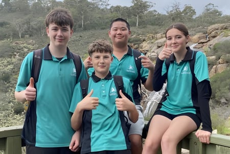Vier Schülerinnen und Schüler der Lakeland Senior High School stehen gemeinsam auf einer Holzbrücke mit Blick auf eine bewaldete Landschaft.