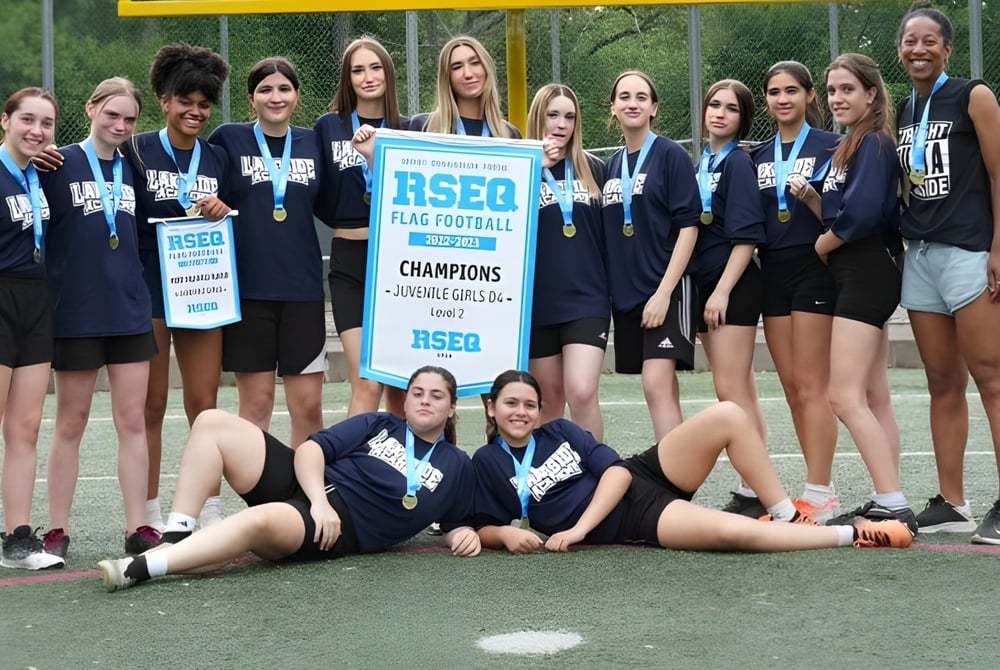 Eine Gruppe Schülerinnen der Lakeside Academy feiert auf dem Sportfeld den Sieg beim Flag-Football-Turnier mit einem Pokal.