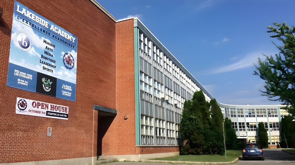 Das Backsteingebäude der Lakeside Academy ist umgeben von Bäumen unter klarem blauen Himmel.