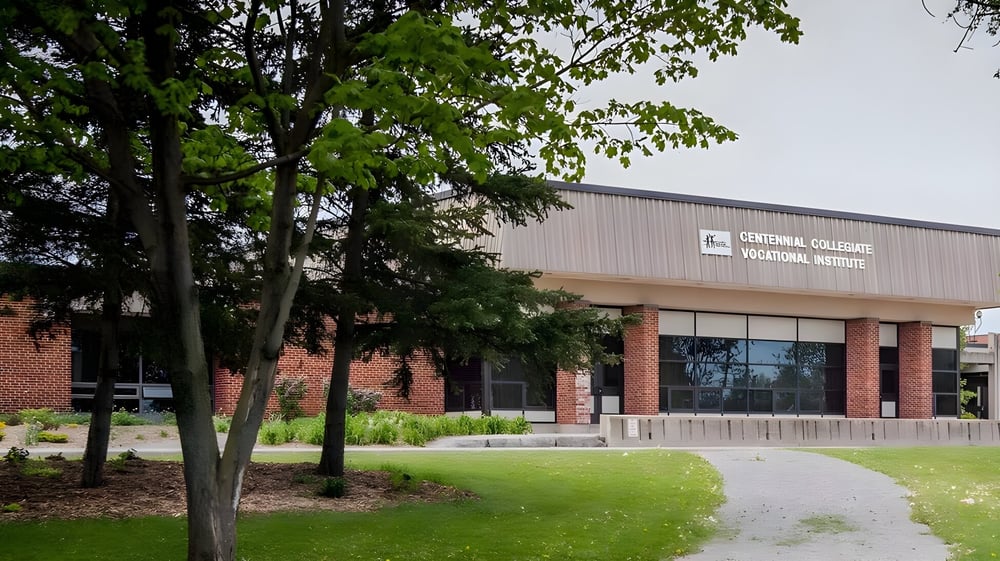 Das Backsteingebäude des Lambton Central Collegiate & Vocational School ist von Bäumen und einer Grasfläche umgeben.