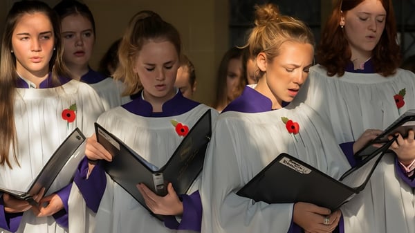 Eine Gruppe von Schülerinnen in weißen Roben mit Büchern im Innenbereich auf dem Campus des Lancing College.