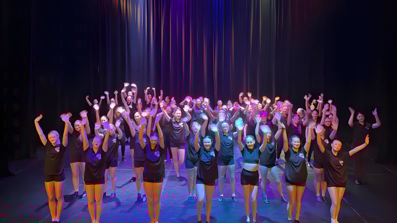 Eine Gruppe von Schülern der Landau Forte Academy Amington steht auf der Bühne und hebt gemeinsam die Arme in einem Auftritt.