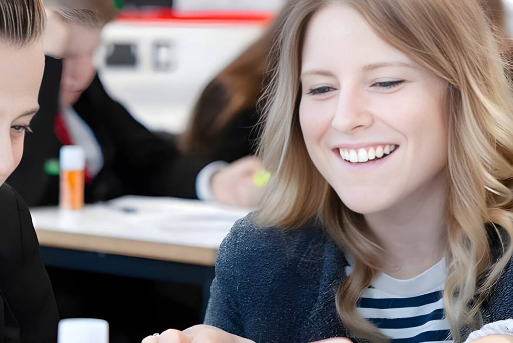 Zwei Schülerinnen und Schüler der Landau Forte Academy Amington lachen gemeinsam in einem ungezwungenen Umfeld.