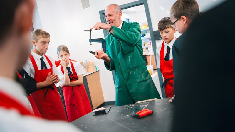Schüler in roten Uniformen hören einem Mann in grünem Gewand bei einer Demonstration auf dem Campus der Landau Forte Academy Amington zu.