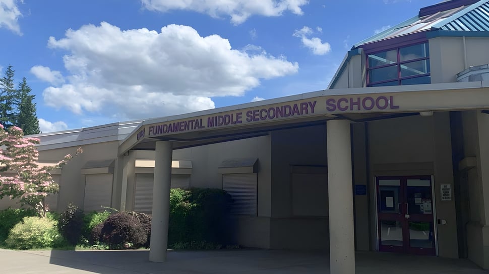 Das moderne Schulgebäude der Langley Fundamental Middle and Secondary School steht vor einem blauen Himmel mit weißen Wolken.