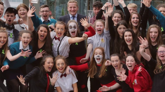 Eine Gruppe von Schülerinnen am Largy College hebt die Hände gemeinsam in Feierlichkeit.
