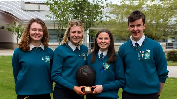 Vier Schüler in Schuluniformen stehen gemeinsam vor einem Gebäude auf dem Campus des Largy College.