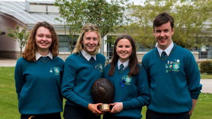 Vier Schülerinnen und Schüler in einheitlichen Schuluniformen stehen gemeinsam auf dem Campus des Largy College.