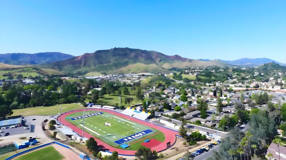 Das Sportfeld des Las Virgenes Unified School District mit grüner Umgebung und Bergen im Hintergrund unter blauem Himmel.
