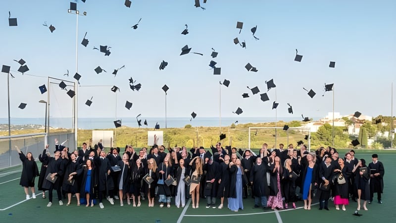 Schülerinnen und Schüler der Laude Lady Elizabeth School feiern ihre Abschlussfeier auf dem Sportfeld und werfen ihre Hüte in die Luft.
