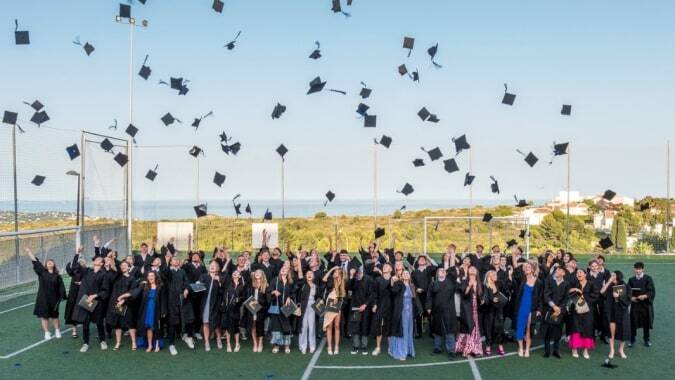 Absolventinnen und Absolventen der Laude Lady Elizabeth School feiern auf dem Sportfeld und werfen ihre Abschlusskappen in die Luft.