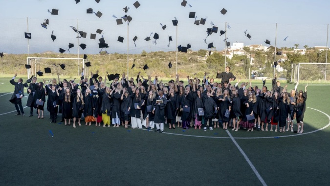 Absolventinnen und Absolventen der Laude Lady Elizabeth School feiern auf dem Sportplatz mit dem Hochwerfen ihrer Abschlussmützen.