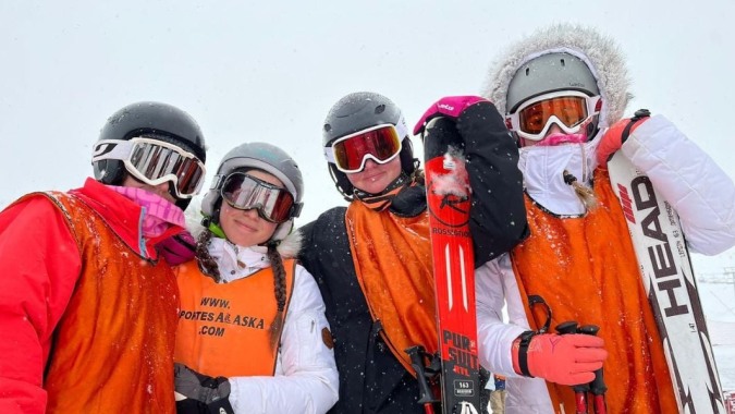 Eine Gruppe von Schülern der Laude Lady Elizabeth School trägt bunte Skiausrüstung bei einem Ausflug im Schnee.
