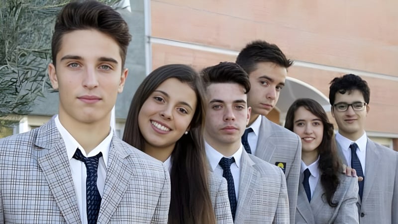 Eine Gruppe Schülerinnen und Schüler der Laude Lady Elizabeth School steht zusammen vor einer Backsteinmauer.