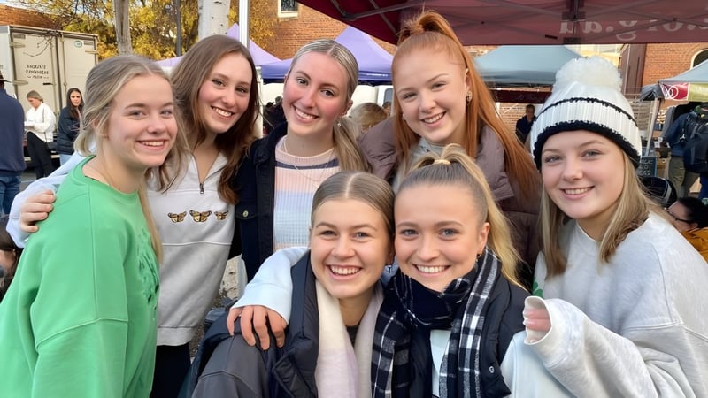 Eine Gruppe junger Schülerinnen steht auf dem Campus des Launceston College vor buntem Herbstlaub.