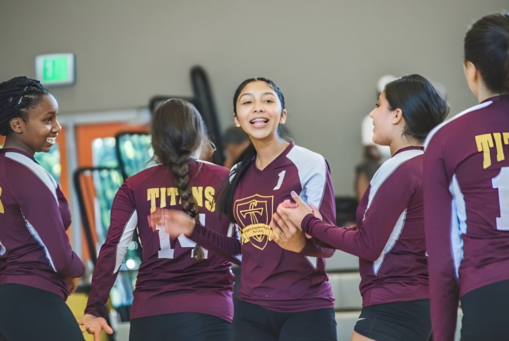 Eine Gruppe Schülerinnen der LaurenHill Academy steht in Sportuniform in einer Sporthalle und unterhält sich miteinander.