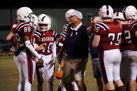 Schüler und ein Coach der Laurens Academy stehen in Fußballuniform auf einem Spielfeld bei Nacht.