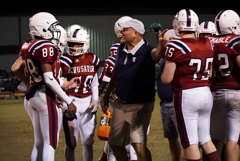 Schüler und ein Coach der Laurens Academy stehen in Fußballuniform auf einem Spielfeld bei Nacht.